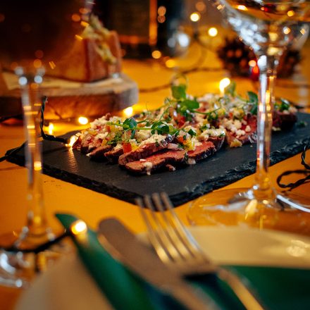 Carpaccio op leisteen bij kaarslicht aan een gedekte kersttafel bij Aards
