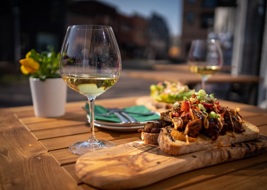 Glas witte wijn naast een gerecht op een houten plank bij Aards in Berkel-Enschot
